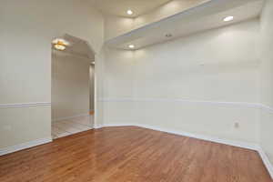 Spare room featuring arched walkways, light wood-style flooring, and recessed lighting