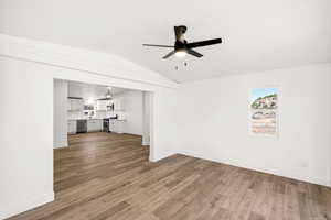 Unfurnished living room featuring light wood finished floors, lofted ceiling, and a ceiling fan
