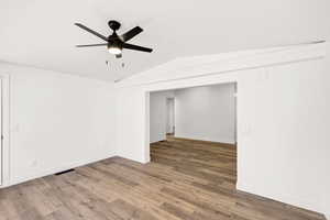 Unfurnished room featuring lofted ceiling, wood finished floors, and ceiling fan
