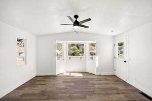 Unfurnished room with vaulted ceiling, dark wood-style floors, a ceiling fan, and a textured ceiling