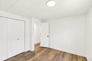 Unfurnished bedroom featuring a closet, light wood-style flooring, and a textured ceiling