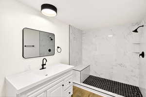 Bathroom featuring a marble finish shower and vanity