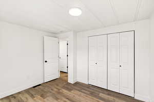 Unfurnished bedroom with wood finished floors and a closet