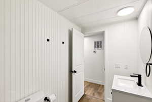 Bathroom featuring vanity, wood finished floors, and wooden walls