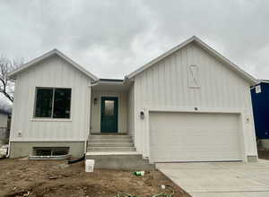 View of front of property with board and batten siding, a garage, and concrete driveway