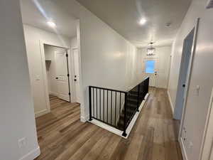 Hallway with an upstairs landing, hardwood / wood-style floors, recessed lighting, and a chandelier
