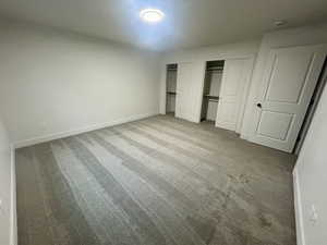 Unfurnished bedroom with multiple closets and light carpet