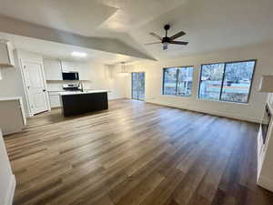 Unfurnished living room featuring light wood finished floors, vaulted ceiling, a chandelier, a textured ceiling, and ceiling fan
