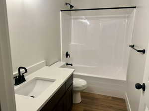 Full bath featuring vanity, bathtub / shower combination, and dark wood-type flooring