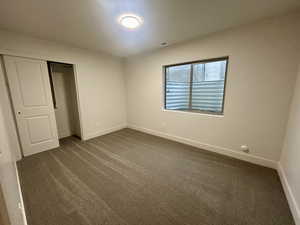 Unfurnished bedroom featuring dark colored carpet and a closet