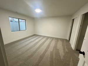 Unfurnished bedroom featuring light carpet and baseboards