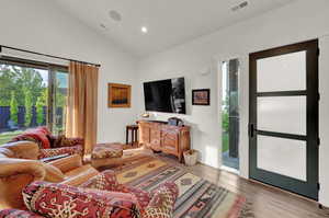 Living area featuring vaulted ceiling, light wood-style flooring, and recessed lighting