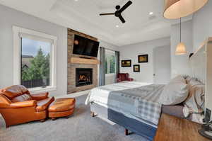 Bedroom featuring wood ceiling, a raised ceiling, a fireplace, carpet floors, and ceiling fan