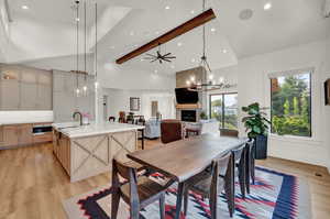 Dining space with a chandelier, ceiling fan, light wood-type flooring, beam ceiling, and high vaulted ceiling