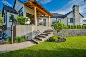 View of front of property with stairs, a patio, a front lawn, and a chimney