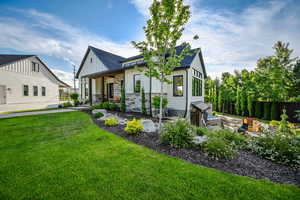 Back of house featuring board and batten siding, a shingled roof, a porch, and stone siding