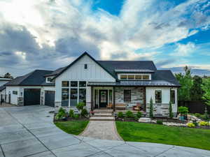 Modern inspired farmhouse with a standing seam roof, stone siding, a metal roof, and covered porch