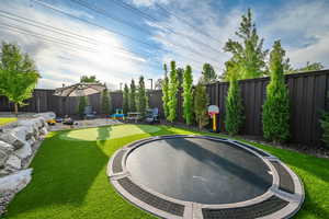 Fenced backyard featuring an area to practice putting and a patio area