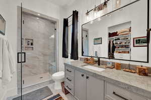 Full bathroom featuring light marble finish floors, a spacious closet, vanity, and a marble finish shower