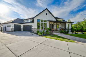 Modern farmhouse style home featuring stone siding, concrete driveway, board and batten siding, and a front yard