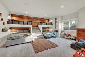 Carpeted bedroom with recessed lighting and wood walls