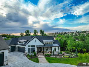 Modern inspired farmhouse featuring stone siding, a standing seam roof, a metal roof, concrete driveway, and board and batten siding