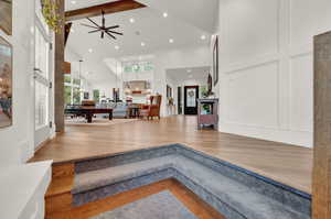 Foyer entrance featuring wood finished floors, a decorative wall, ceiling fan, high vaulted ceiling, and beamed ceiling