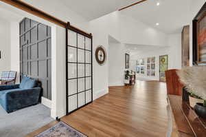 Foyer entrance featuring a barn door, wood finished floors, recessed lighting, and high vaulted ceiling