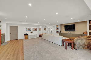 Living room with built in shelves, light wood finished floors, and recessed lighting