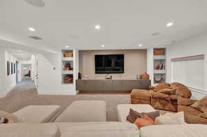 Living area with built in features, light colored carpet, and recessed lighting