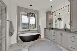 Full bathroom with a chandelier, double vanity, a freestanding bath, light marble finish floors, and recessed lighting