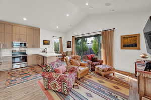 Living room featuring light wood-style floors, high vaulted ceiling, and recessed lighting