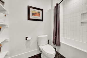 Full bathroom with toilet and shower / bath combo with shower curtain