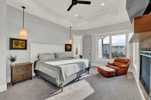 Bedroom featuring a raised ceiling, carpet floors, ceiling fan, a fireplace, and wooden ceiling
