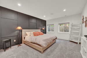 Bedroom featuring a decorative wall, recessed lighting, and light carpet