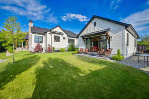 Rear view of house with a patio area, a standing seam roof, a chimney, a metal roof, and board and batten siding