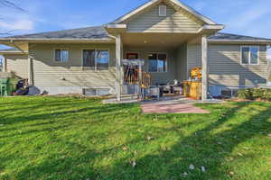 Rear view of property with a lawn, a patio, and a shingled roof