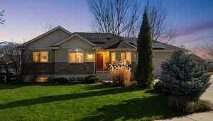 View of front of property with a lawn, solar panels, an attached garage, and stone siding