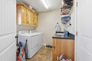 Laundry area featuring cabinet space, washing machine and dryer, and stone finish flooring
