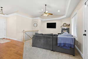 Living area featuring ornamental molding, a raised ceiling, hardwood / wood-style flooring, a ceiling fan, and recessed lighting