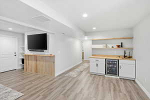 Indoor bar with open shelves, wine cooler, white cabinets, recessed lighting, and light wood-type flooring