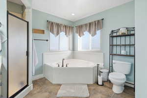 Full bathroom featuring a shower stall, a garden tub, and a baseboard radiator