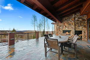 View of patio featuring an outdoor stone fireplace and outdoor dining area