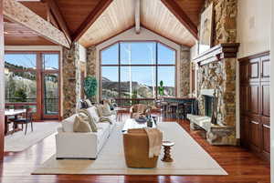 Living room featuring high vaulted ceiling, a fireplace, dark wood-type flooring, a wood ceiling with exposed beams, and a mountain view