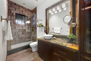 Full bathroom featuring vanity, a tile shower, and stone tile flooring