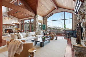 Living room with a fireplace, high vaulted ceiling, wood-type flooring, a mountain view, and a wooden ceiling with exposed beams
