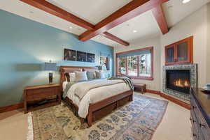 Bedroom featuring beamed ceiling, a glass covered fireplace, recessed lighting, and carpet