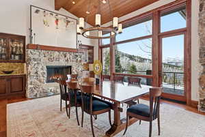 Dining space with wood-type flooring, a wood ceiling with exposed beams, a fireplace, a chandelier, and a mountain view