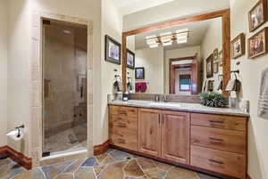Bathroom with vanity, a stall shower, and stone tile flooring
