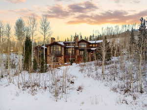 Snow covered back of property with a chimney
